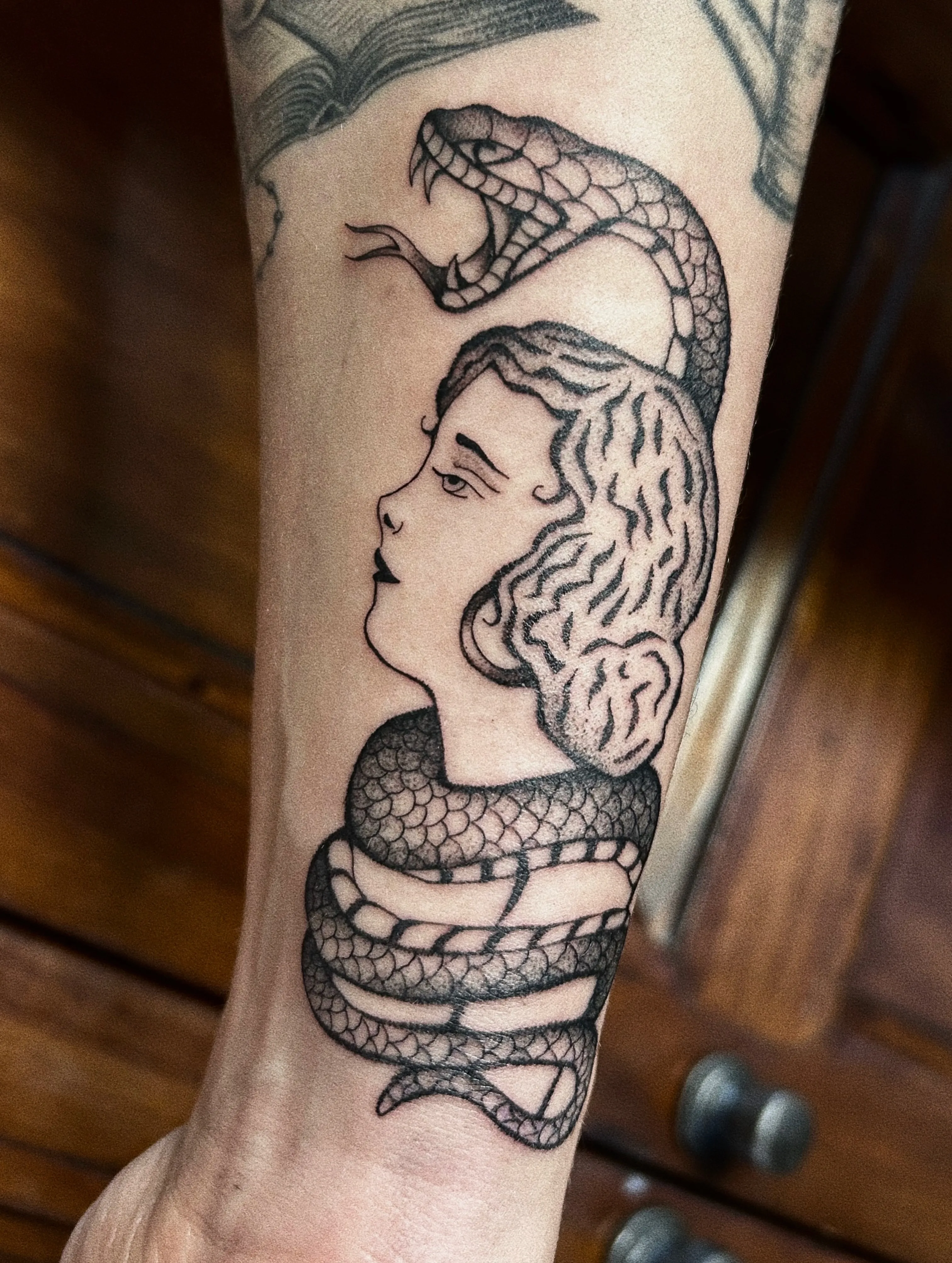 Black and grey forearm tattoo — classical profile with a serpent