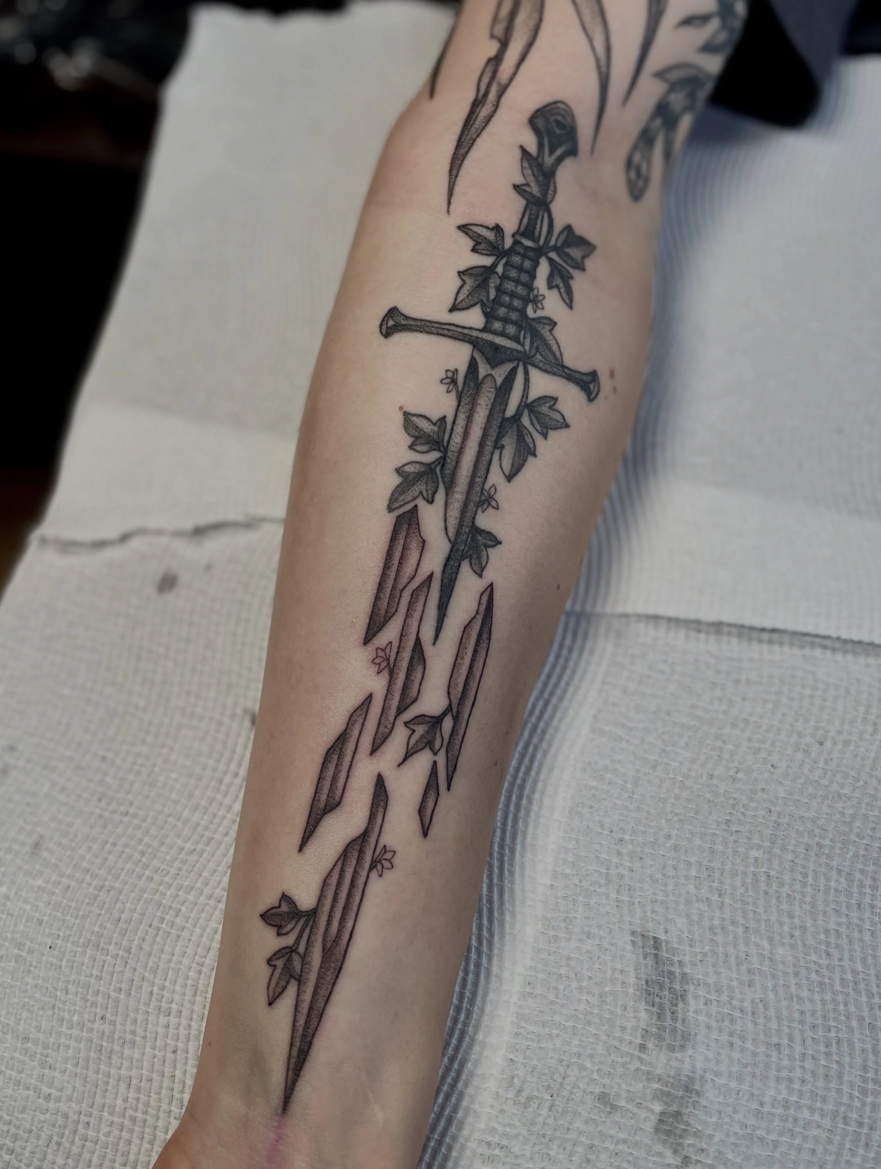 Black and grey forearm tattoo — medieval dagger wrapped in ivy